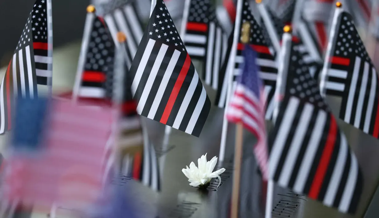 Bunga dan bendera Amerika Serikat terlihat di atas nama-nama korban serangan teroris 9/11 di kolam refleksi Menara Selatan selama Upacara Peringatan Tahunan 9/11 di Museum dan Monumen Nasional 9/11 di Kota New York pada 11 September 2025. (Michael M. Santiago/Getty Images North America/Getty Images via AFP)