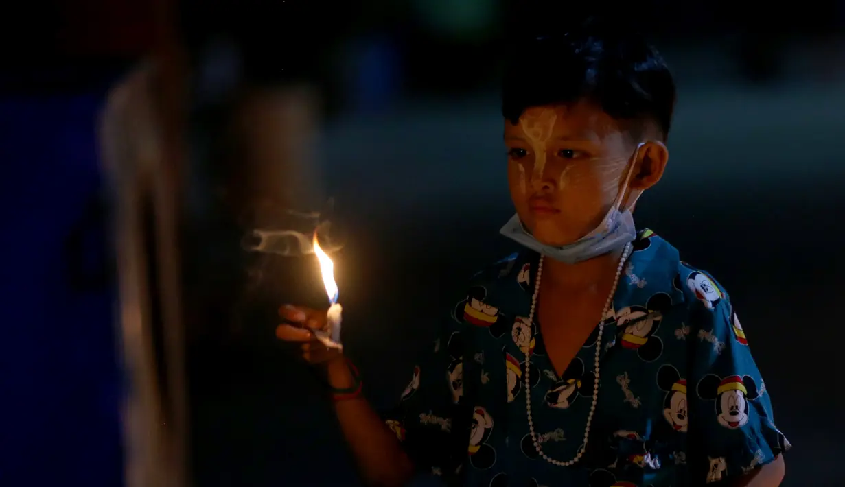 Seorang anak menyalakan lilin saat Festival Tazaungdaing di Yangon, Myanmar (29/11/2020). Festival itu dirayakan di Myanmar sebagai hari libur nasional dan menandai akhir musim hujan. (Xinhua/U Aung)