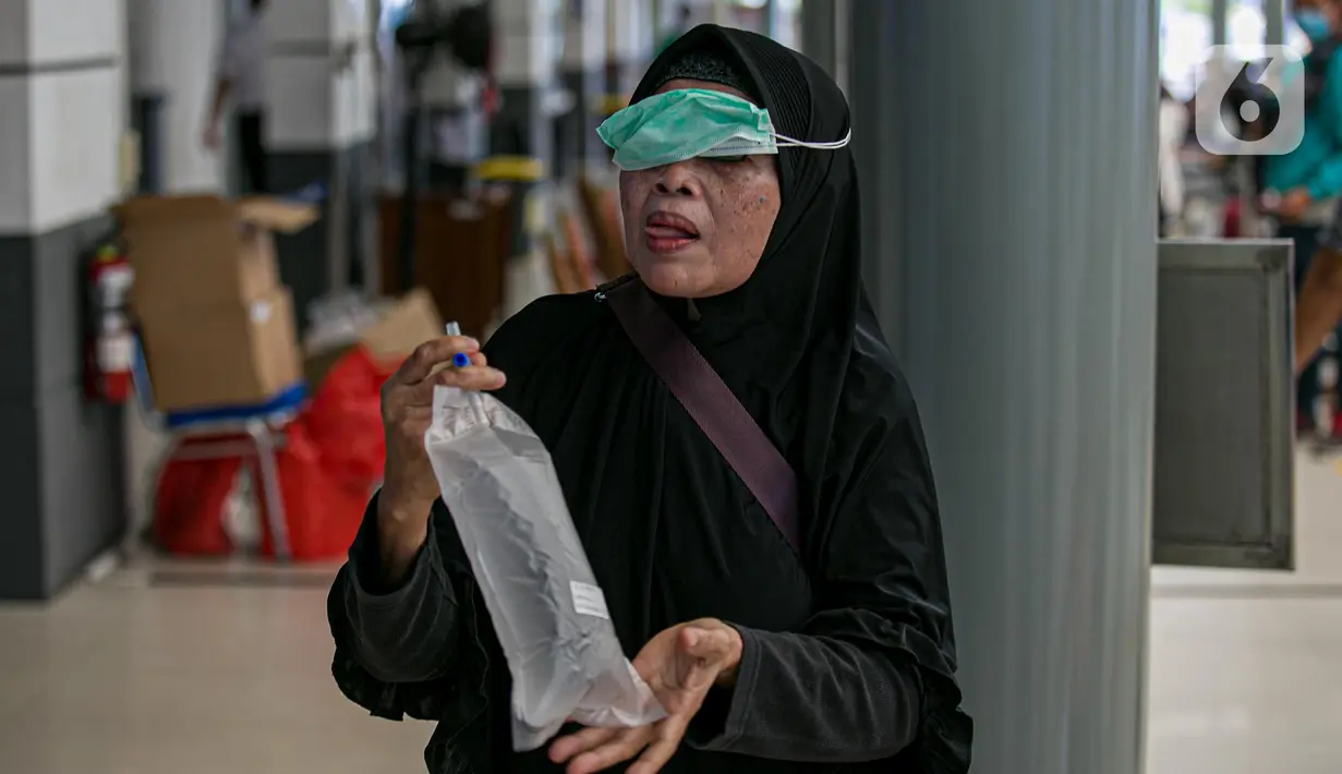 Calon penumpang kereta api menutup kantong berisi nafasnya yang kemudian dites COVID-19 dengan GeNose C19 di Stasiun Pasar Senen, Jakarta, Jumat (5/2/2021). PT Kereta Api Indonesia memberlakukan calon penumpang menjalani GeNose C19 untuk tes COVID-19. (Liputan6.com/Faizal Fanani)