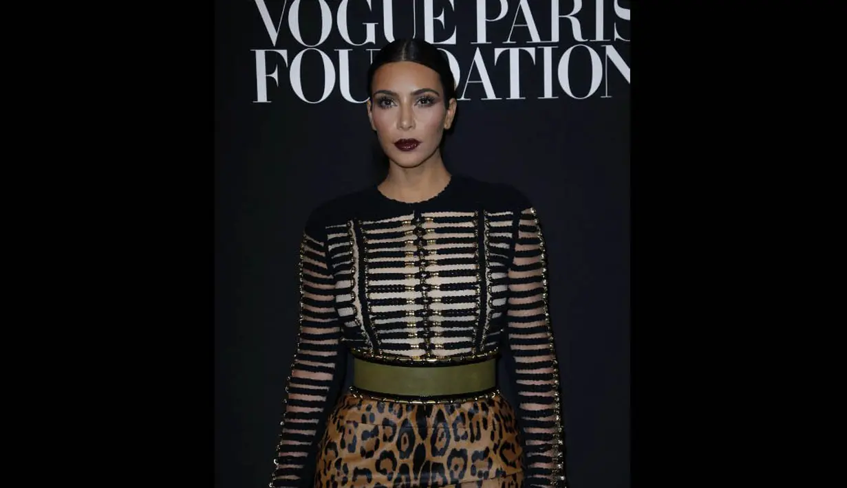 Ibu dari North West itu mengenakan rok pensil bermotif macan tutul dengan ikat pinggang hijau yang dipadukan dengan baju lengan panjang hitam dan emas saat hadir dalam sebuah acara di Paris Fashion Week 2014, Rabu (9/7/14). (AFP PHOTO/Thomas Samson)