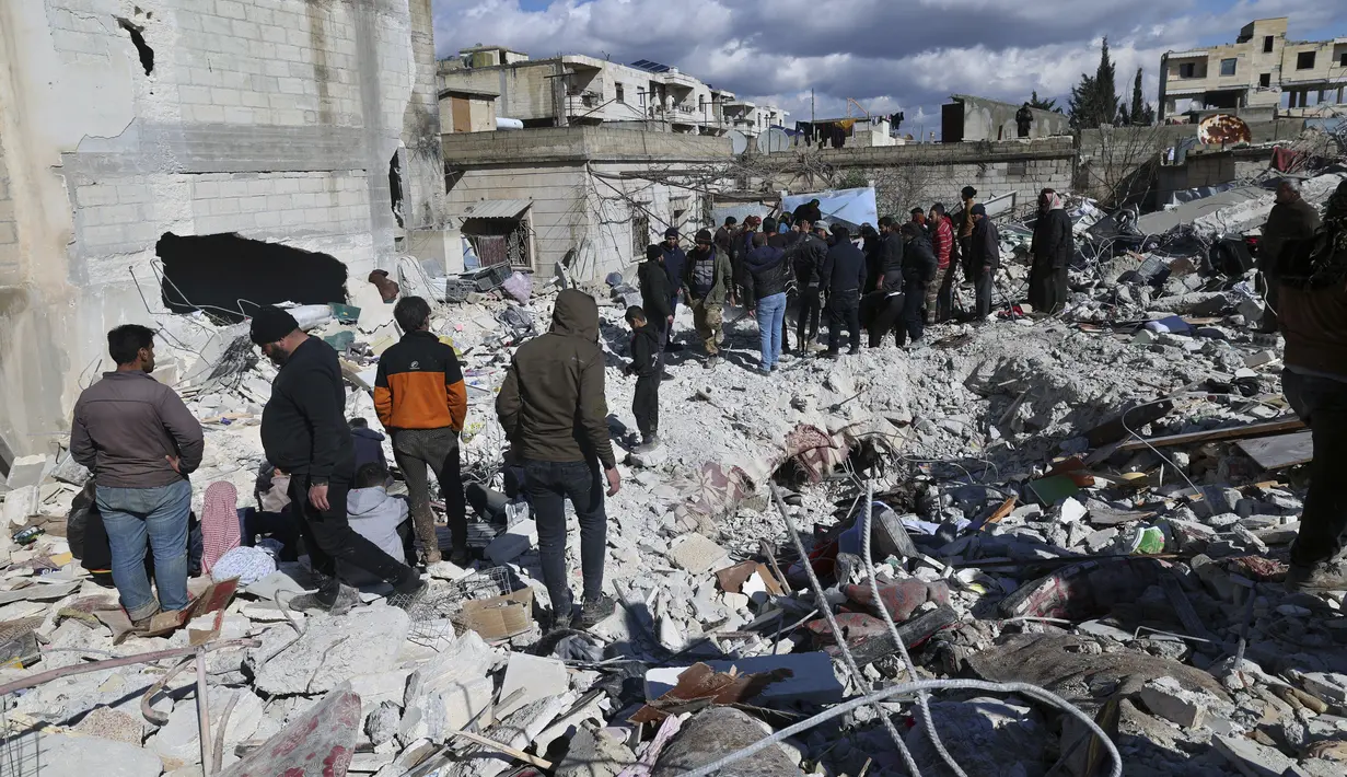 Orang-orang mencari melalui puing-puing bangunan yang runtuh tempat bayi perempuan yang baru lahir ditemukan di kota Jinderis, provinsi Aleppo, Suriah, Selasa (7/2/2023). Dokter anak Hani Maarouf mengatakan kepada AFP bahwa kondisi bayi tersebut stabil tetapi terdapat memar, luka robek, dan hipotermia. (AP Photo/Ghaith Alsayed)