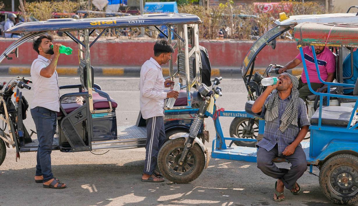 Pengemudi becak listrik minum air pada siang hari yang panas di New Delhi, India, Rabu 20 Mei 2026. (AP Photo/Manish Swarup)
