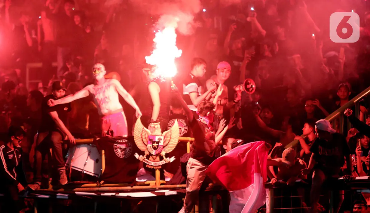 Suporter menyalakan suar jelang berakhirnya laga Timnas Indonesia U-19 melawan Vietnam U-19 pada kualifikasi grup A Piala AFF U-19 2022 di Stadion Patriot Candrabhaga, Bekasi, Jawa Barat, Sabtu (2/7/2022). Selama menyaksikan laga, para suporter terus meneriakkan yel-yel dukungan untuk Timnas Indonesia U-19. (Liputan6.com/Helmi Fithriansyah)