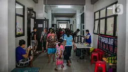 Sejumlah korban banjir berjalan di lorong gedung SDN 01/02 Kampung Melayu, Jakarta, Selasa (9/2/2021). Gedung sekolah di Kebon Pala tersebut menjadi salah satu posko pengungsian bagi sebagian korban banjir Kampung Melayu. (Liputan6.com/Faizal Fanani)
