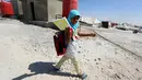Seorang anak perempuan berjalan membawa buku menuju sekolah mengikuti hari pertama tahun ajaran baru sekolah di sebuah kamp di Ain Issa, Suriah (22/8). (AFP Photo/Delil souleiman)