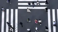 Warga yang mengenakan masker untuk membantu mengekang penyebaran COVID-19 berjalan di sepanjang penyeberangan pejalan kaki di Tokyo, Jepang, Selasa (27/7/2021). Tokyo melaporkan jumlah kasus harian COVID-19 tertinggi beberapa hari setelah Olimpiade dimulai. (AP Photo/Eugene Hoshiko)