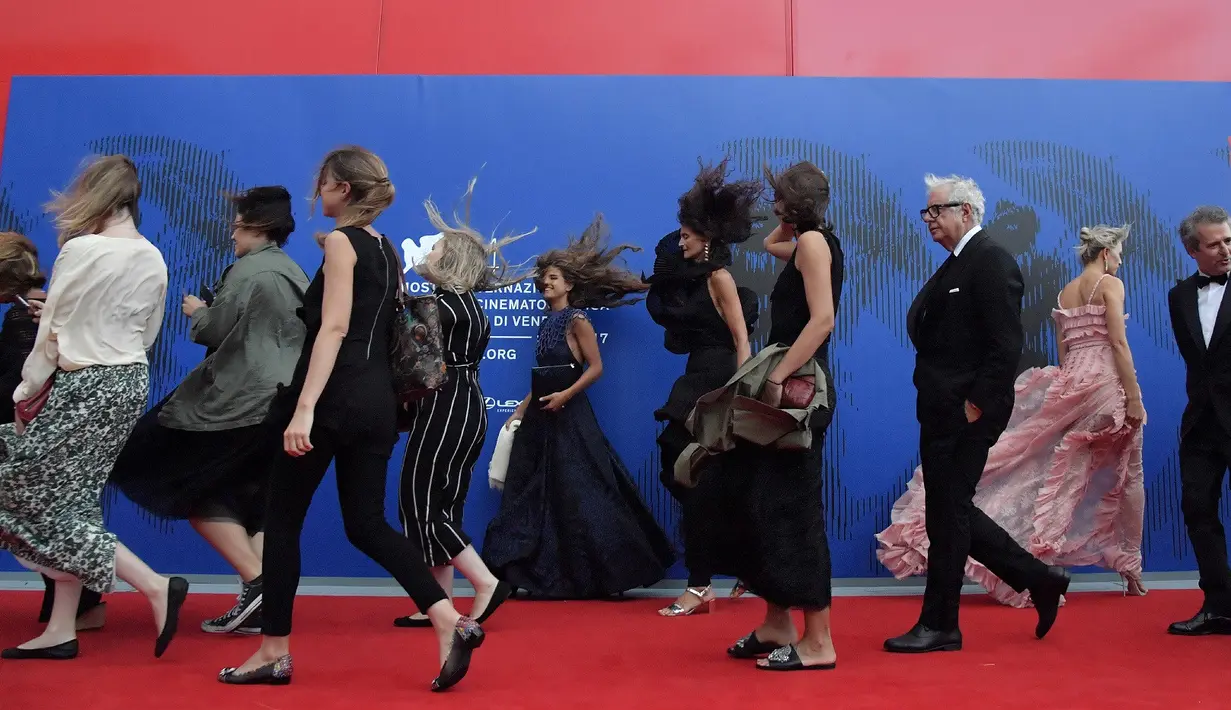 Sejumlah selebriti tertiup angin saat berjalan menghadiri "Penghargaan Franca Sozzani" selama Festival Film Venice ke-74 di Venice Lido (1/9). (AFP Photo/Tizianaa Fabi)