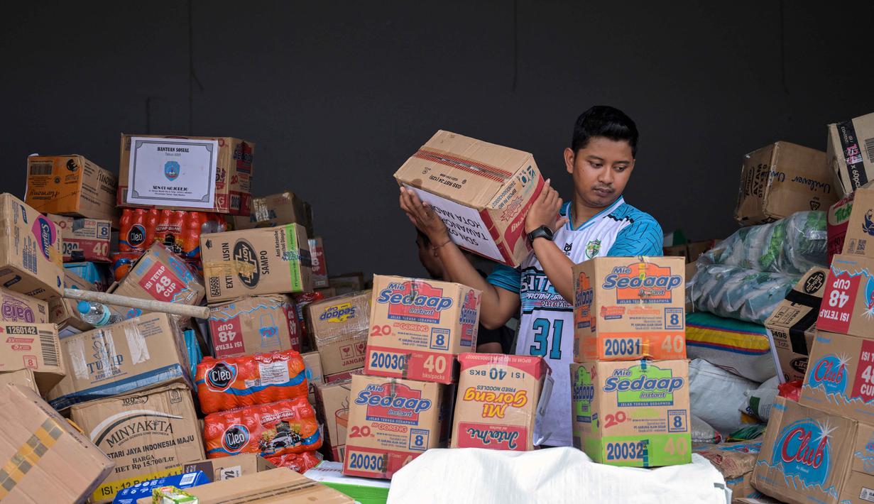 Di antaranya, 13,5 ton bantuan akan dialokasikan untuk korban di Medan, Sumatera Utara, sementara 13 ton lainnya dikirim ke Aceh. Tampak dalam foto, seorang relawan mengemas perbekalan untuk dikirimkan ke daerah-daerah terdampak banjir di Badan Penanggulangan Bencana Daerah (BPBD) Sidoarjo, Provinsi Jawa Timur, pada Jumat 5 Desember 2025. (JUNI KRISWANTO/AFP)