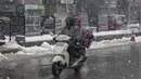 Seorang pria Kashmir mengendarai skuter saat salju turun di Srinagar, Kashmir yang dikuasai India (15/1/2020). Selama dua hari terakhir wilayah Himalaya telah menyaksikan hujan salju lebat yang mengakibatkan serangkaian longsoran dan tanah longsor. (AP Photo/Dar Yasin)
