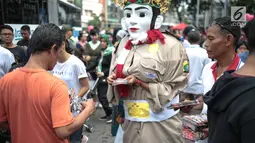 Petugas bersama ondel-ondel membagikan brosur sosialisasi E-Tilang saat car free day di bunderan HI, Jakarta, Minggu (28/10). Kegiatan sosialisasi E-Tilang tersebut agar masyarakat lebih mengetahui sanksi yang akan diberikan. (Liputan6.com/Faizal Fanani)