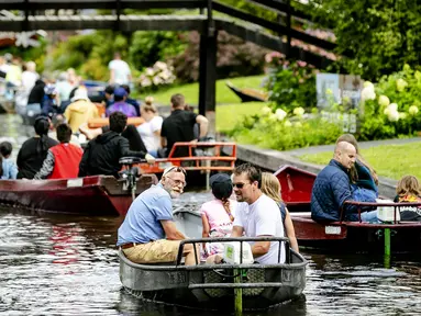 Wisatawan menaiki perahu menyusuri sungai di Giethoorn yang menjadi tujuan wisata favorit di Belanda pada 6 Agustus 2019. Mendapat julukan 'Venice of the North', kota tersebut menggunakan kanal-kanal sebagai jalan dan lalu lalang transportasi sehari-hari. (Robin van Lonkhuijsen/ANP/AFP)