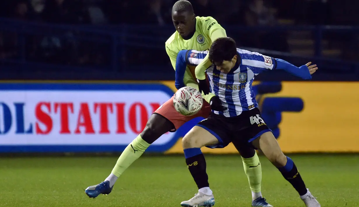 Bek sayap Manchester City, Benjamin Mendy, berebut bola dengan pemain Sheffield Wednesday, Fernando Forestieri pada putaran kelima Piala FA di Hillsborough, Rabu (4/3/2020).Sempat kesulitan, Manchester City akhirnya menang tipis 1-0 atas Sheffield Wednesday lewat gol Sergio Aguero. (AP/Rui Vieira)
