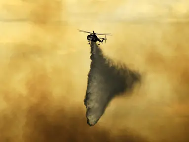 Helikopter menjatuhkan tembakan pada api yang terbakar di dekat Evergreen, Colo (13/7/2020). Cuaca dingin dan hujan yang turun memberikan harapan kepada petugas pemadam kebakaran untuk dapat mengendalikan api yang menyebabkan kebakaran di wilayah tersebut. (RJ Sangosti/The Denver Post via AP)