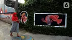 Warga berjalan dekat mural yang menghiasi tembok rumah warga RT 02/RW 07 Kampung Warna-warni, Kelurahan Pengadegan, Jakarta Selatan, Selasa (10/12/2019). Mural di kampung ini dibuat dari dana swadaya warga setempat. (merdeka.com/Imam Buhori)
