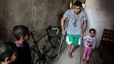 Atlet sepeda asal Palestina, Alaa Al-Daly berjalan menggunakan kruk di rumahnya di Rafah, Jalur Gaza, 19 April 2018. Impian atlet 21 tahun itu untuk berkompetisi di ajang Asian Games seketika pupus karena kaki kanannya diamputasi. (AFP/SAID KHATIB)
