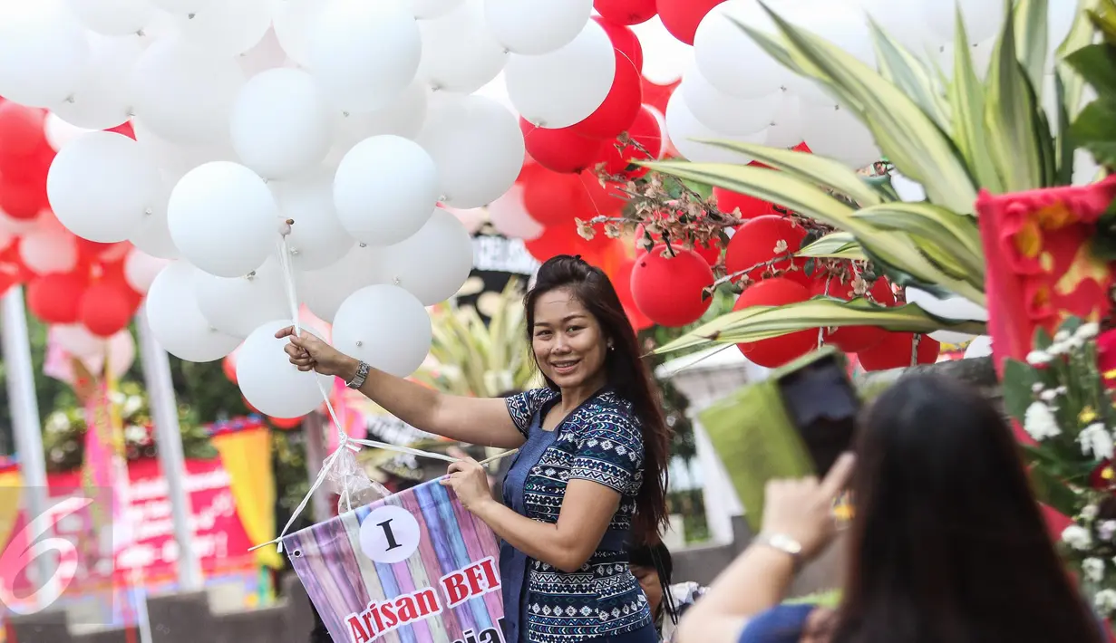 Seorang warga berpose sambil memegang balon yang berada di halaman Balai Kota, Jakarta, Senin (8/5). Balon itu merupakan bentuk dukungan moril untuk Ahok yang besok akan menjalani sidang putusan kasus dugaan penodaan agama. (Liputan6.com/Faizal Fanani)