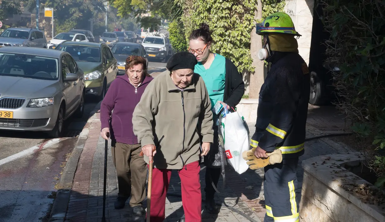 Sejumlah warga meninggalkan rumah mereka akibat kebakaran hutan hebat yang melanda kota utara Israel, Haifa, Kamis (24/11). Kebakaran terjadi setelah kekeringan selama dua bulan dan diikuti dengan angin kencang di utara kota itu. (JACK GUEZ/AFP)