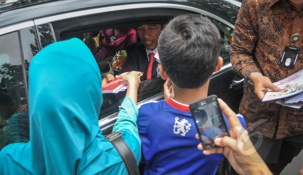Presiden Joko Widodo (Jokowi) saat membagikan buku kepada kerumunan warga di Jalan Cicendo, Bandung, Jumat (24/4/2015). (Liputan6.com/Faizal Fanani)