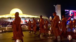 Biksu Buddha membawa lilin selama perayaan Makha Bucha di kuil Wat Dhammakaya di provinsi Pathum Thani, utara Bangkok (16/2/2022). Makha Bucha merupakan salah satu hari raya terpenting bagi para penganut agama Buddha. (AFP/Jack Taylor)