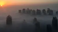 Matahari terbit memancarkan sinar yang berwarna oranye keemasan diantara gedung pencakar langit di Kota Dubai, Uni Emirat Arab, Senin (5/12). Biasanya kabut ini muncul saat musim panas yang terik berubah ke musim dingin yang cukup sejuk. (AFP/Rene Slama)