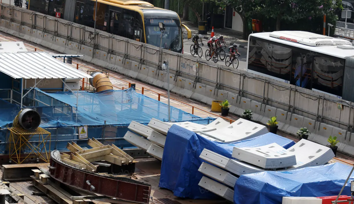 Para pebalap bersaing diantara Bus Trans Jakarta saat melewati ruas jalan protokol Sudirman pada ajang Tour de Jakarta di Bundaran Hotel Indonesia, Jakarta, Sabtu (30/7/2016). (Bola.com/Nicklas Hanoatubun)
