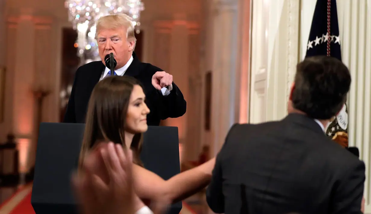 Presiden AS, Donald Trump mengarahkan telunjuk ke jurnalis CNN Jim Acosta saat seorang staf mencoba menarik mikrofon darinya dalam konferensi pers di Gedung Putih, Rabu (7/11). Ketegangan bermula dari pertanyaan sang wartawan soal imigran. (AP/Evan Vucci)