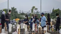 Keluarga berdoa untuk kerabat mereka di lokasi pemakaman korban virus corona COVID-19 di TPU Keputih, Surabaya, Jawa Timur, Sabtu (17/7/2021). Di Kota Surabaya terdapat dua tempat lahan pemakaman khusus blok COVID-19 yakni TPU Keputih dan TPU Babat Jerawat. (JUNI KRISWANTO/AFP)