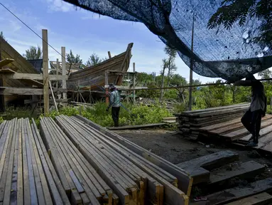 Pekerja memuat material untuk membuat kapal nelayan di Banda Aceh, Aceh pada 21 November 2020. Industri galangan kapal tradisional di daerah itu mengalami kesulitan memperoleh bahan baku kayu untuk memproduksi kapal nelayan, sehingga berdampak pada proses penyelesaian kapal. (CHAIDEER MAHYUDDIN/AFP)