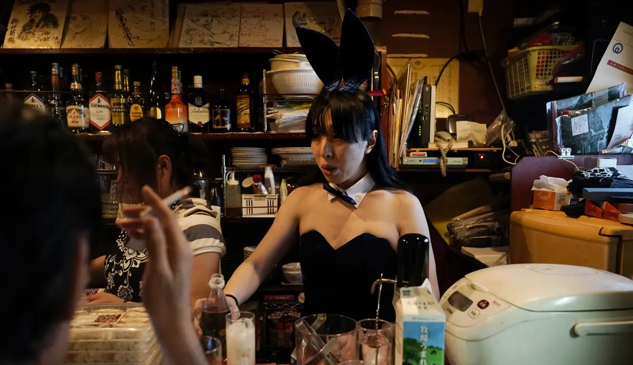 Bartender menyiapkan minuman untuk seorang pengunjung di sebuah bar di Golden Gai di distrik Shinjuku, Tokyo (26/7/2019). Shinjuku Golden Gai adalah daerah kecil di Kabukicho, Shinjuku, Tokyo, Jepang, yang terkenal baik sebagai bidang minat arsitektur dan kehidupan malamnya. (AFP Photo/Jae C. Hong)