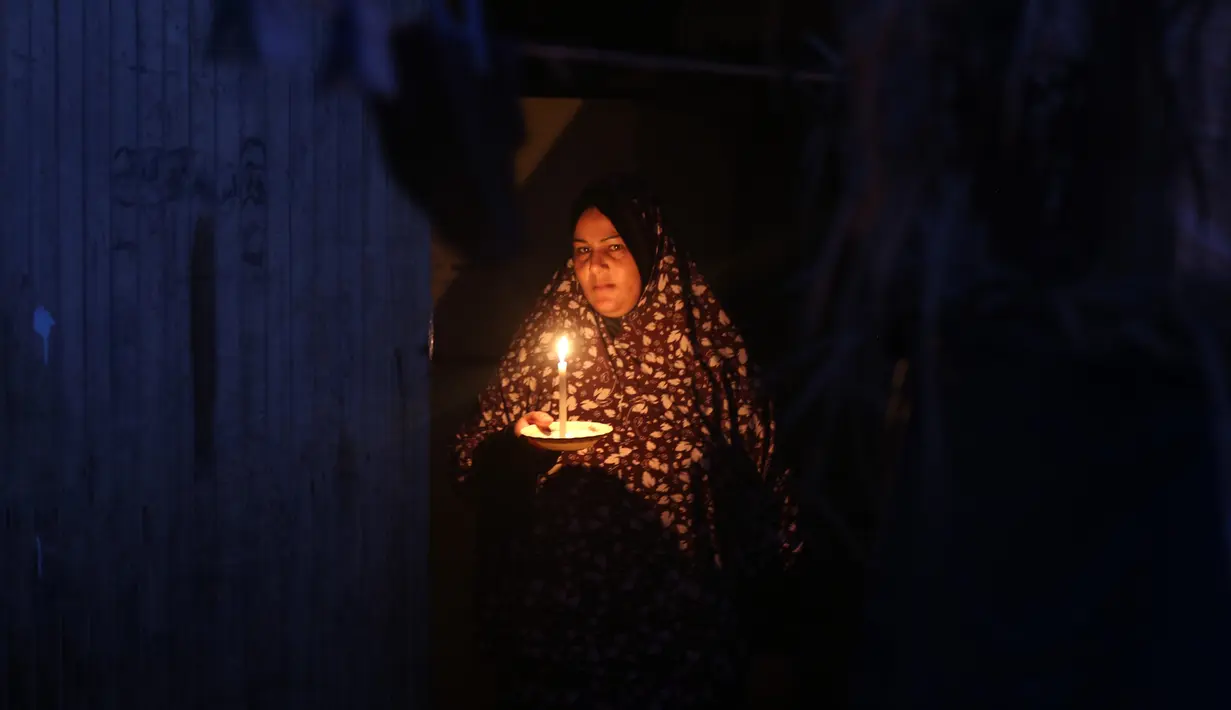 Seorang perempuan Palestina terlihat membawa lilin di depan rumahnya saat pemadaman listrik terjadi di Kota Khan Younis, Jalur Gaza selatan, pada 18 Agustus 2020. Satu-satunya pembangkit listrik di Jalur Gaza telah sepenuhnya berhenti beroperasi akibat kehabisan bahan bakar. (Xinhua/Yasser Qudih)