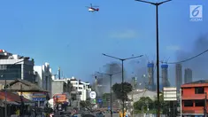 Helikopter water bombing menyiramkan air ke arah ban yang dibakar massa di kawasan Slipi, Jakarta, Rabu (22/5/2019). Air dijatuhkan dari udara ke arah api yang berasal dari ban bekas. (merdeka.com/Arie Basuki)