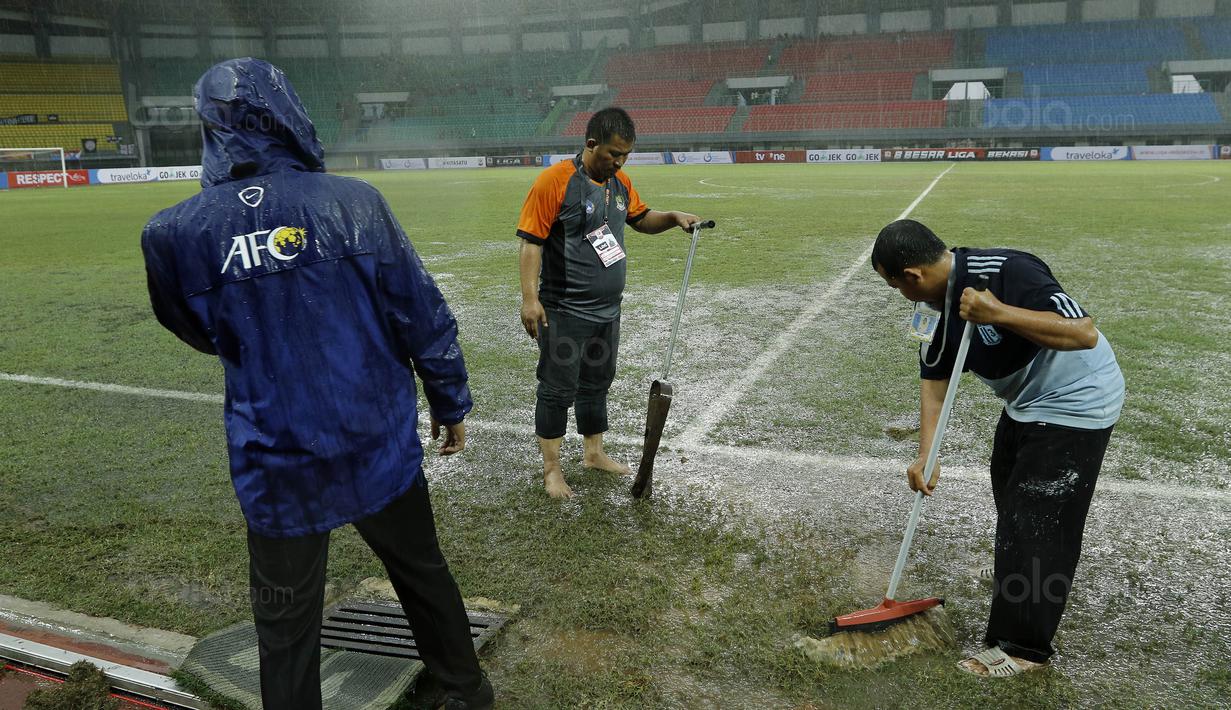 Para petugas berusaha menguras air yang menggenangi lapangan di Stadion Patriot, Bekasi, Senin (13/11/2017). Drainase yang buruk menyebabkan lapangan terendam air. (Bola.com/M Iqbal Ichsan)