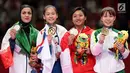 Karateka putri Indonesia, Cokorda Istri Agung Sanistyarani (kedua kanan) menunjukkan medali perunggu usai memenangkan pertandingan di babak final nomor Kumite 55 kg di Arena Karate JCC Senayan, Jakarta, Minggu (26/8). (Liputan6.com/Fery Pradolo)
