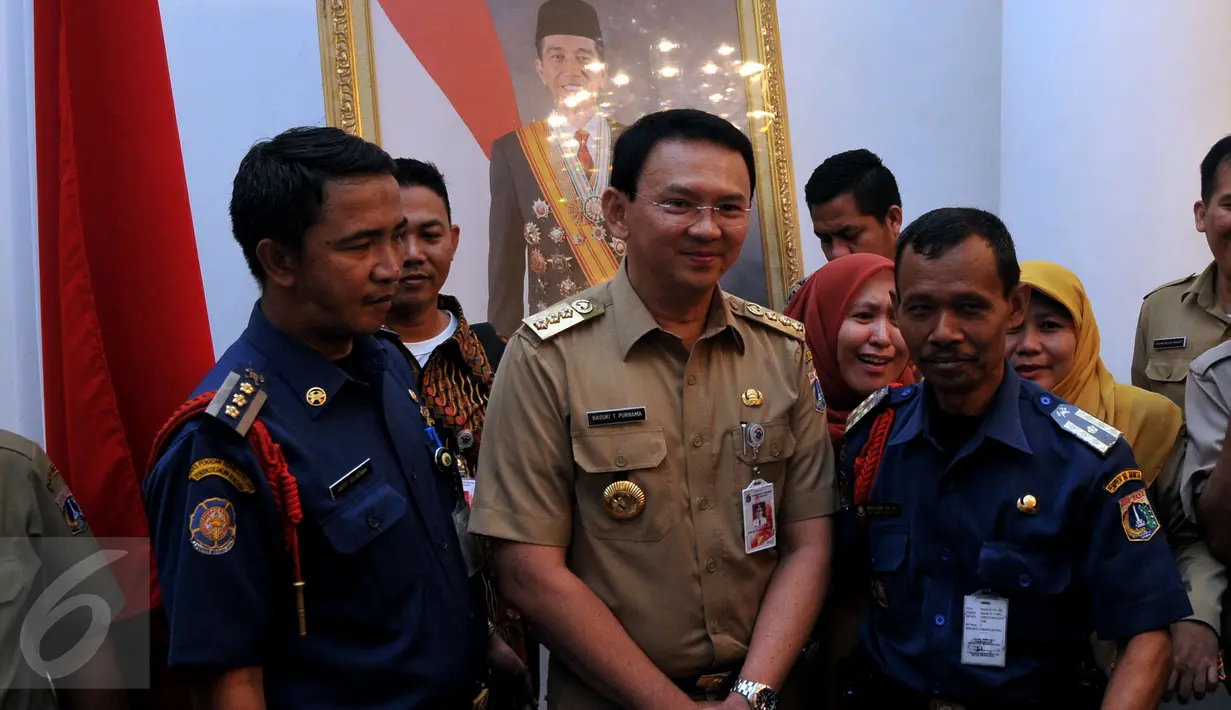 Tampak Gubernur DKI Jakarta Basuki T Purnama berfoto dengan dua Pegawai Negeri Sipil (PNS) di Balai Kota, Jakarta, Rabu (22/7/2015). Pada sela - sela kunjungannya mereka memanfaatkan momen dengan berfoto bersama Gubernur. (Liputan6.com/JohanTallo)