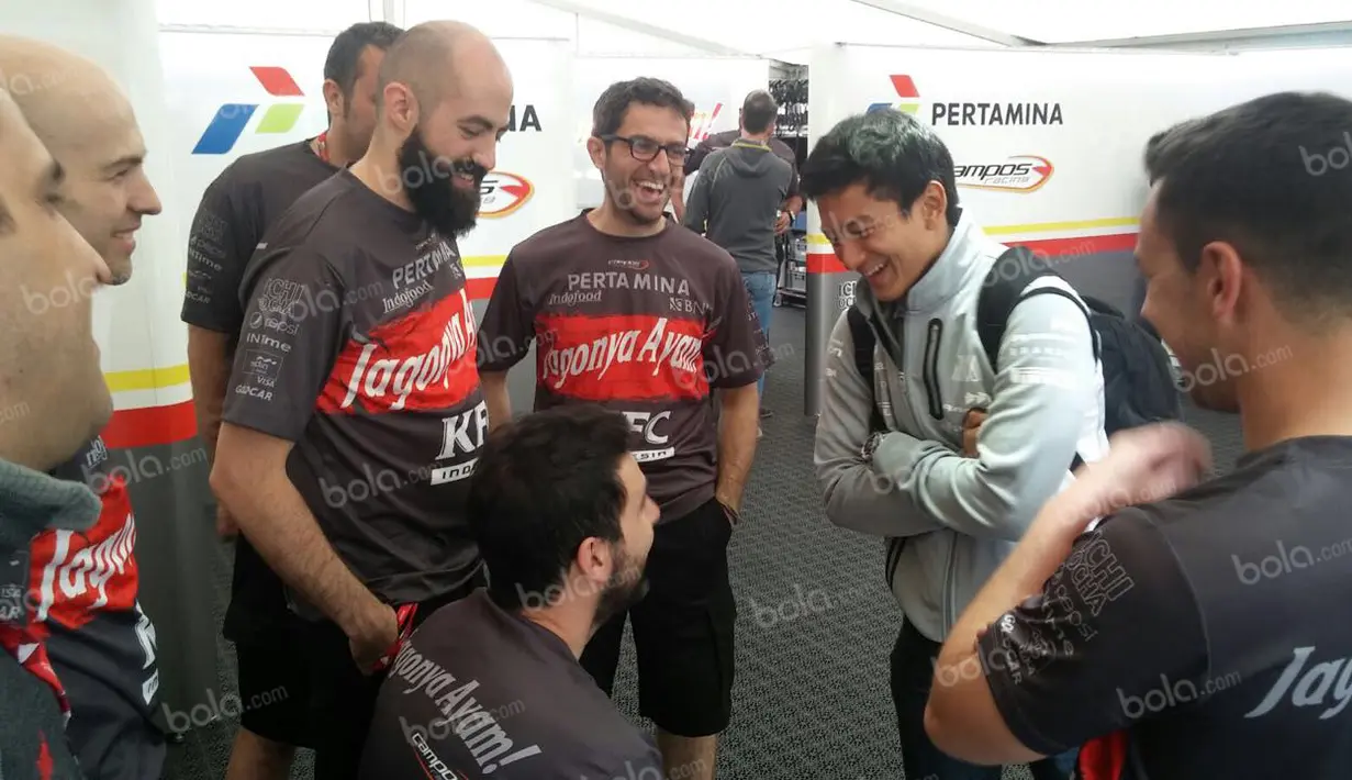 Pebalap Manor Racing asal Indonesia, Rio Haryanto, bercanda dengan kru Pertamina Campos Racing saat berkunjung ke paddock di Sirkuit Catalunya, Spanyol, Sabtu (14/5/2016). Campos Racing adalah mantan tim Rio Haryanto saat di GP2. (Bola.com/Reza Khomaini)