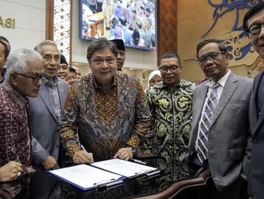 Menko Perekonomian Airlangga Hartarto disaksikan Menko Polhukam Mahfud MD, Menkumham Yasonna Laoly, dan Wakil Ketua Baleg DPR M. Nurdin menandatangani draft Peraturan Pemerintah Pengganti Undang-Undang (Perppu) Cipta Kerja di Kompleks Parlemen, Senayan, Jakarta, Rabu (15/2/2023). Baleg DPR menyetujui untuk membawa Perppu Cipta Keria ke Paripurna dan disahkan menjadi Undang-Undang (UU). (Liputan6.com/Faizal Fanani)