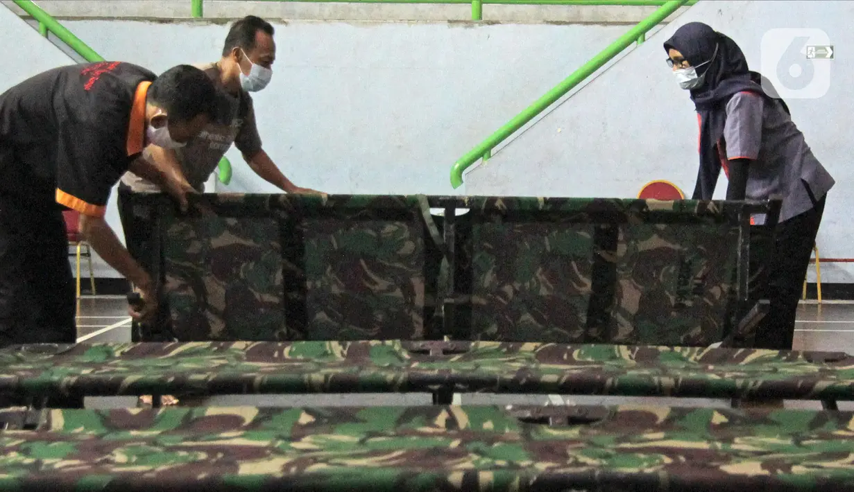 Petugas menyiapkan tempat singgah sementara bagi warga yang baru kembali ke Jakarta di GOR Cipayung, Jakarta, Selasa (18/5/2021). GOR ini jadi tempat singgah bagi mereka yang tidak memiliki tempat layak untuk isolasi mandiri sambil menunggu hasil tes swab antigen/PCR. (Liputan6.com/Herman Zakharia)
