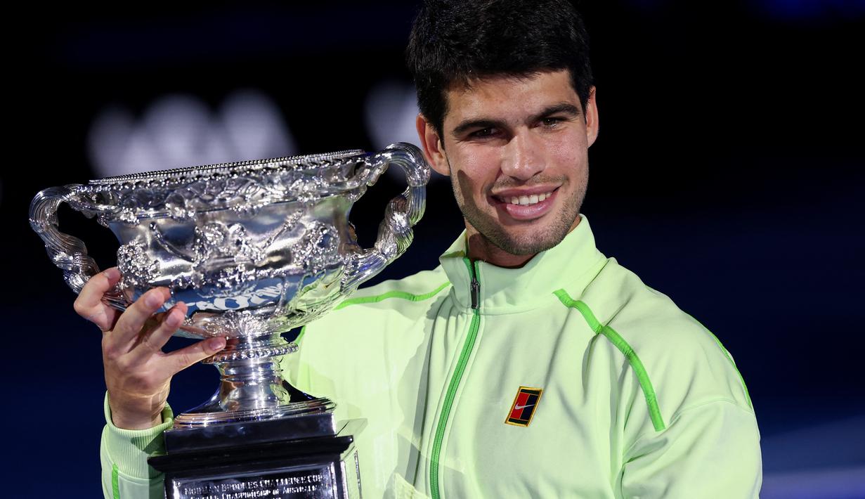 Carlos Alcaraz memamerkan piala usai berhasil menjuarai Australian Open 2026 setelah menaklukkan Novak Djokovic dalam laga sengit yang dilangsungkan di Melbourne Park pada (1/2/2026) sore WIB. (AFP/Izhan Khan)