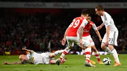 Gelandang Swansea City, Gylfi Sigurdsson (kanan) berusaha melewati dua pemain Arsenal saat Laga Liga Premier Inggris di Emirates Stadium, Selasa (12/5/2015). Swansea City menang 1-0 atas Arsenal. (Reuters/ADylan Martinez)