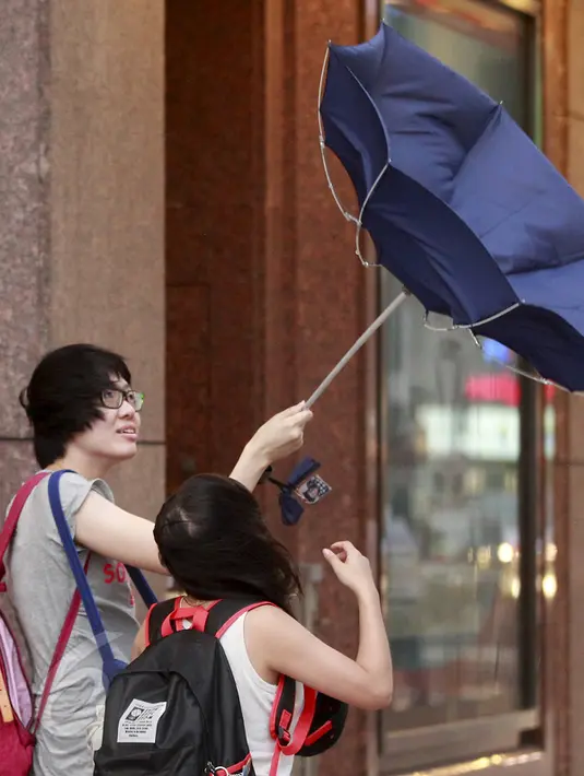 Warga taiwan memegang payung yang rusak akibat tiupan angin kencang saat Topan Soudelor mendekati wilayah Taipei, Taiwan, (7/8/2015). Topan ini diperkirakan akan melanda wilayah Taiwan pada hari Sabtu. (REUTERS/Pichi Chuang)