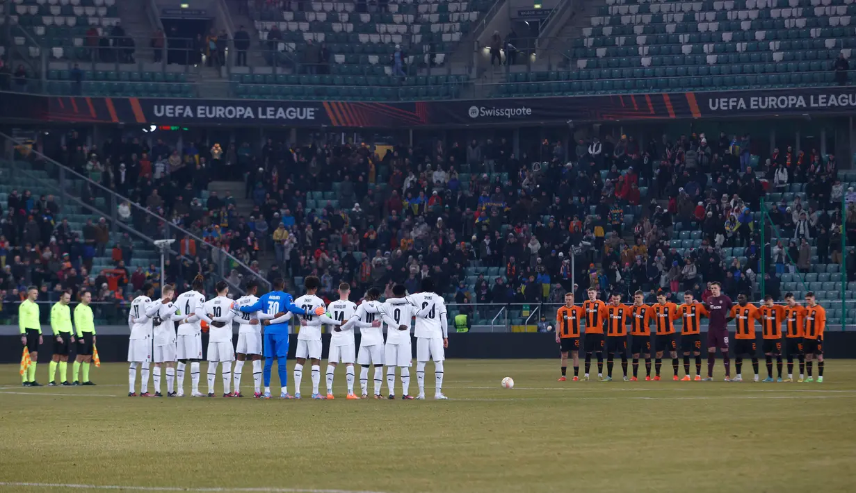 Para pemain berbaris untuk memberikan penghormatan kepada para korban gempa Turki dan Suriah menjelang pertandingan sepak bola Liga Eropa antara Shakhtar Donetsk dan Rennes di Stadion Angkatan Darat Polandia, Warsawa, Polandia, 16 Februari 2023. (AP Photo/Michal Dyjuk)