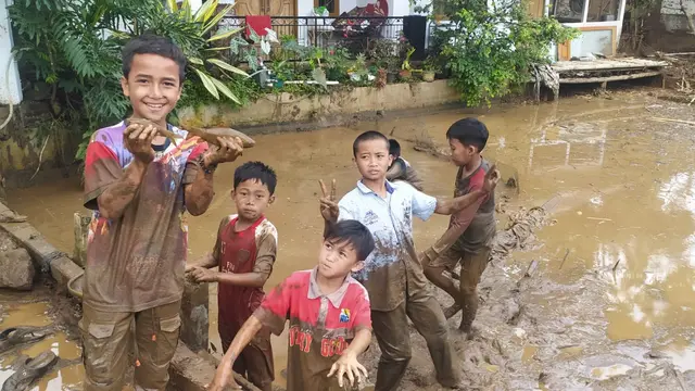 Dengan rona wajah ceria, Firdasu dan rekannya, nampak asik dan ceria ‘ngubek balong’ atau mencari ikan yang tersisa di kolam milik warga setelah musibah banjir bandang menyapu kampungnya.