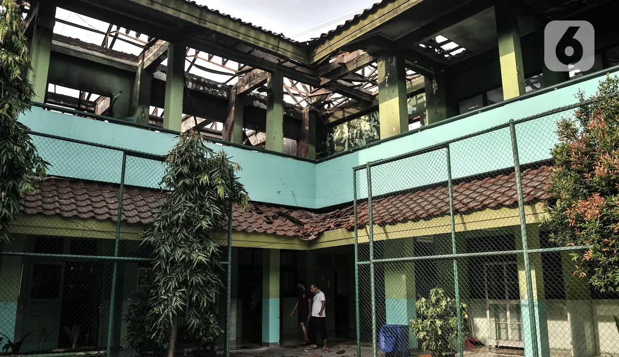 Petugas keamanan melintasi ruangan kelas usai kebakaran melanda SMA Negeri 100 Jakarta, Rabu (1/7/2020). Beruntung tidak ada korban jiwa dalam kebakaran ini, namun sedikitnya tujuh ruangan beserta isinya ludes dilalap si jago merah. (merdeka.com/Iqbal S Nugroho)
