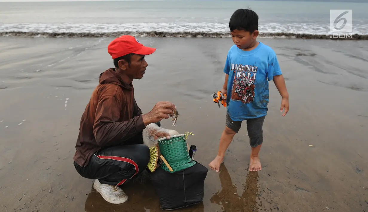 Pencari ikan menunjukkan hasil tangkapannya kepada anak kecil di Pantai Palangpang, Ciletuh, Sukabumi, Jawa Barat, Minggu (22/9). (Merdeka.com/Arie Basuki)