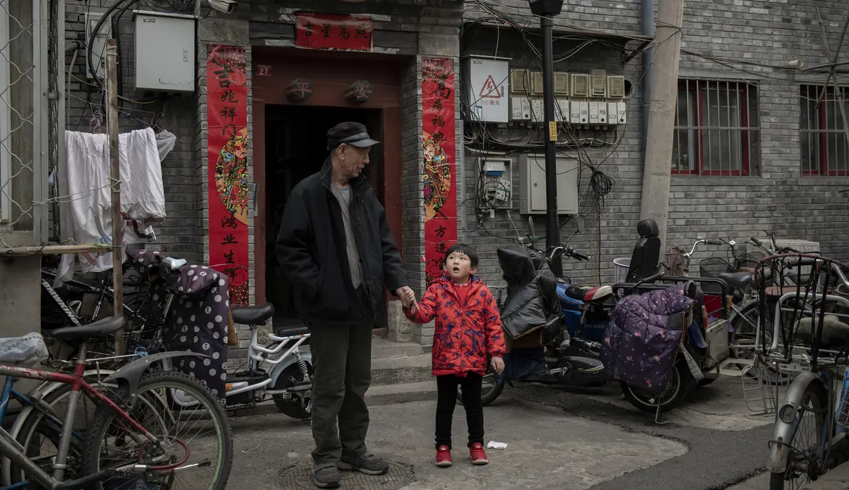 Seorang kakek bersama cucunya berbincang di halaman di luar rumah mereka di daerah hutong di Beijing (26/2). Hutong adalah jenis jalan sempit atau gang yang biasanya dikaitkan dengan kota-kota Cina utara, terutama Beijing.  (AFP Photo/Nicolas Asfouri)
