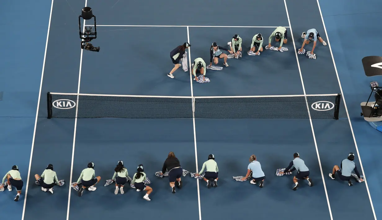 Ball boy mengeringkan Rod Laver Arena saat hujan berhenti selama pertandingan tunggal putaran pertama antara Roger Federer dari Swiss dan Steve Johnson dari Amerika Serikat di kejuaraan tenis Australia Terbuka di Melbourne, Australia, Senin (20/1/2020). (AP Foto/Lee Jin-man)