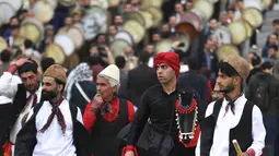 Sekelompok pemain cerita rakyat dari wilayah timur Iran berjalan saat musisi daerah Kurdi memainkan Daf, drum Persia genggam, dalam upacara menjelang Tahun Baru Iran, atau Nowruz, di sebuah taman di Teheran, Iran (14/3/2022). Nowruz akan diselenggarakan pada 20 Maret. (AP Photo/Vahid Salemi)