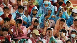 Sejumlah fans Liverpool menggunakan jas hujan saat menyaksikan sesi latihan The Reds di Stadion Rajamangala. (AFP/Jack Taylor)