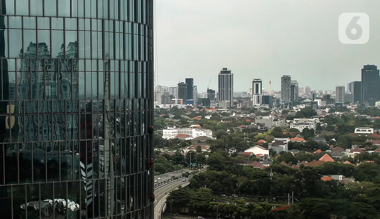 Pekerja bergelantungan membersihkan bagian luar gedung di kawasan Kuningan, Jakarta, Minggu (19/12/2021). Pekerja ini harus bergelantungan dengan seutas tali untuk membersihkan dinding-dinding gedung bertingkat yang tingginya kurang lebih mencapai 150 meter. (Liputan6.com/Johan Tallo)