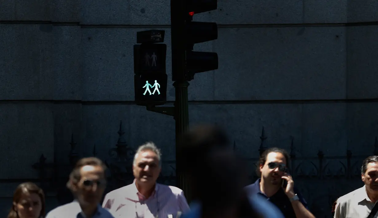 Pejalan kaki melewati lampu lalu lintas berlambang LGBT di Madrid, Spanyol, Selasa (6/6). Pemasangan lampu lalu lintas ini merupakan bagian dari penyambutan Festival WorldPride yang akan digelar akhir bulan ini di Madrid. (AP Photo/Francisco Seco)